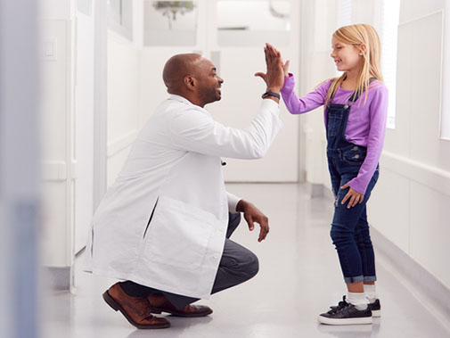 Doctor kneeling and high fiving his young patient
