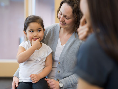 Child in speech therapy while sitting on her mother's lap